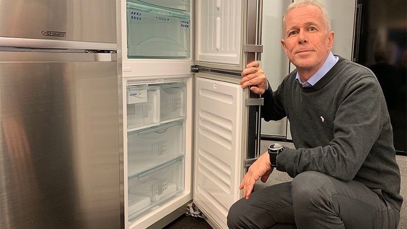 Arne Voll, kommunikasjonssjef i Gjensidige, på huk foran et kjøleskap med døren åpen til fryser og kjøleskap.
