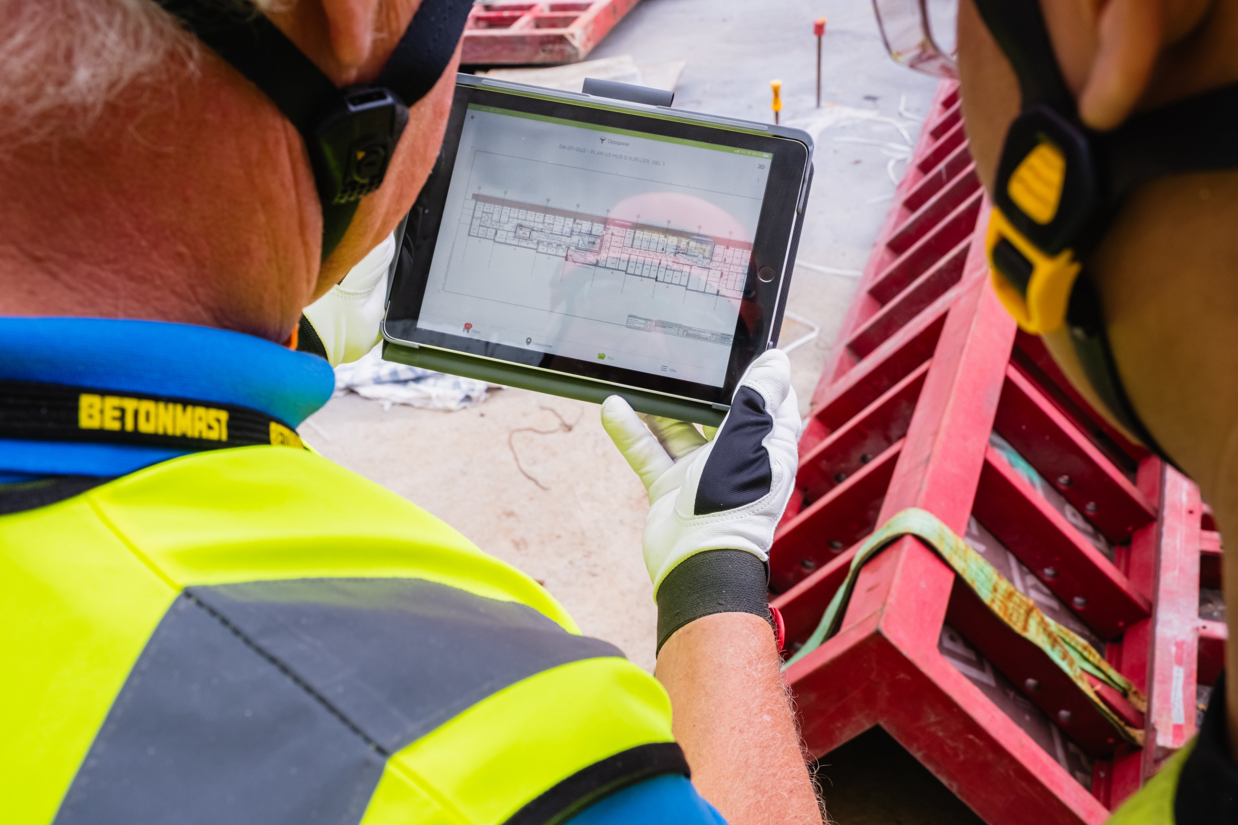 Byggearbeider holder i iPad med plantegninger