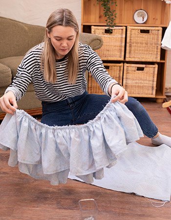 Ingrid Bergtun sittende på gulvet og holde opp et stoff