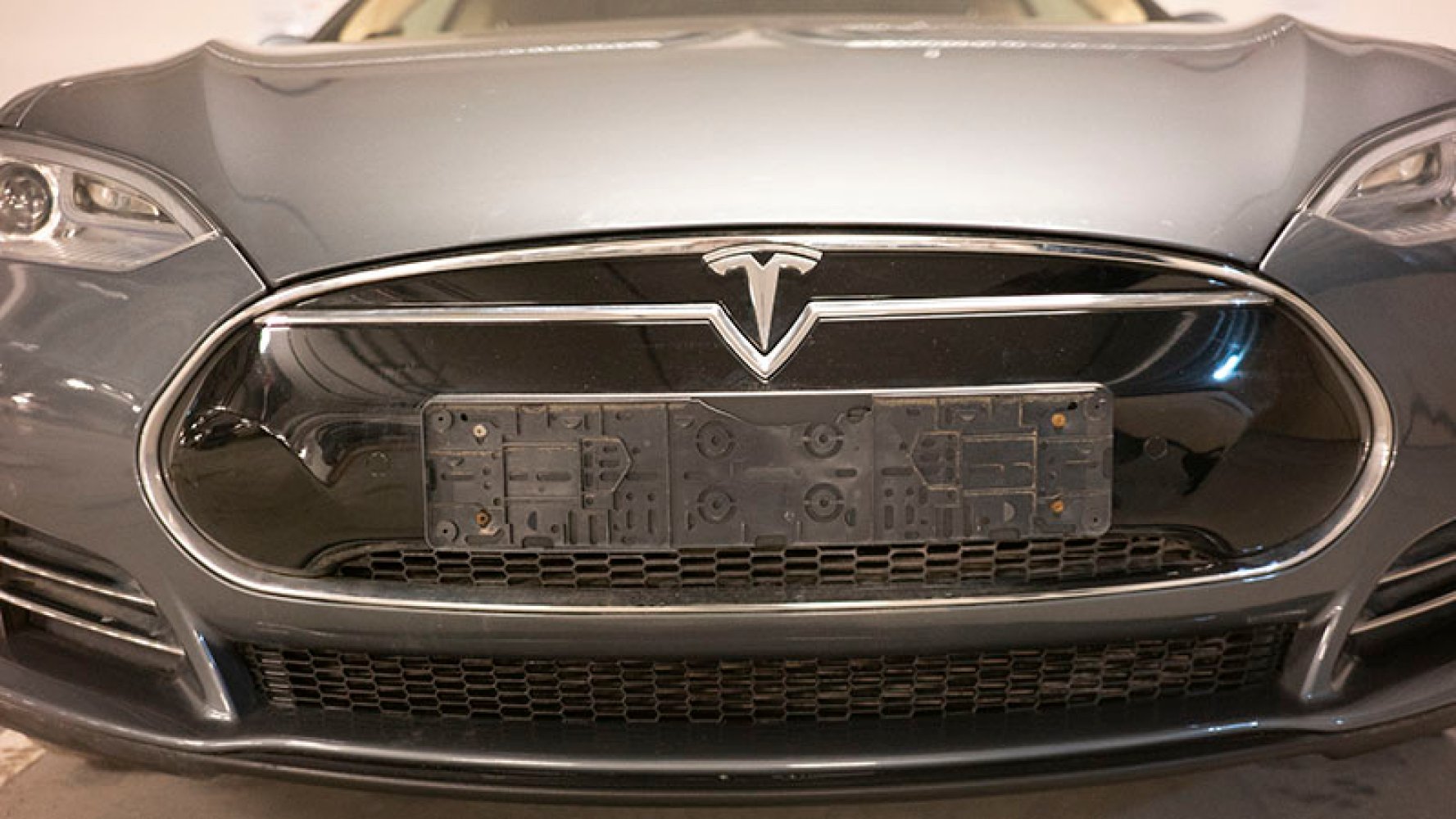 Fronten av en grå Tesla elbil, uten nummerskilt. 
