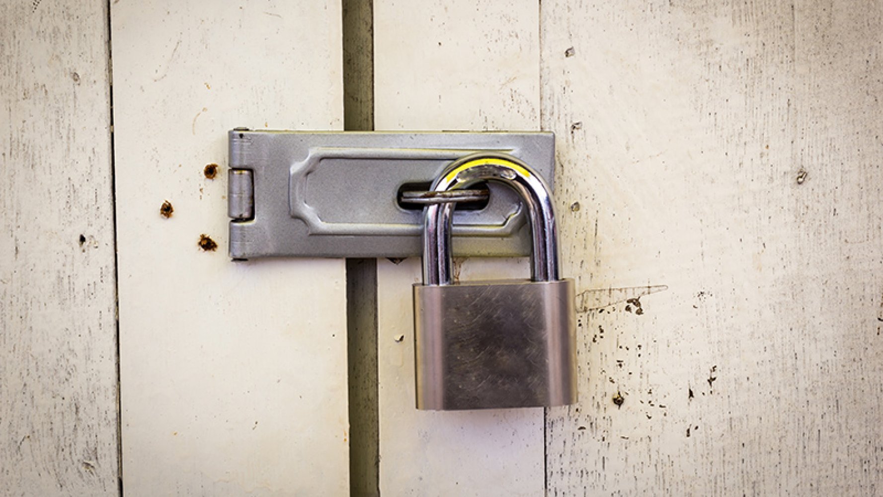 Metallhengelås festet på en hvit treport.