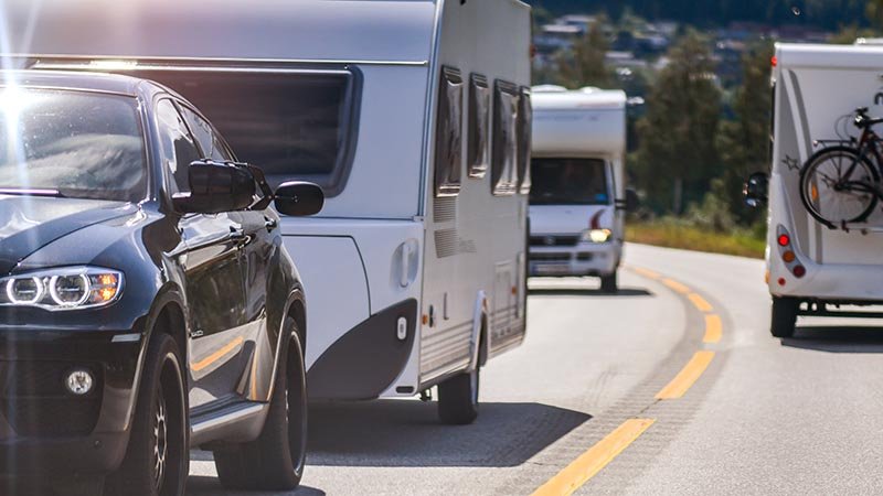 Bil med campingvogn kjører på veien.