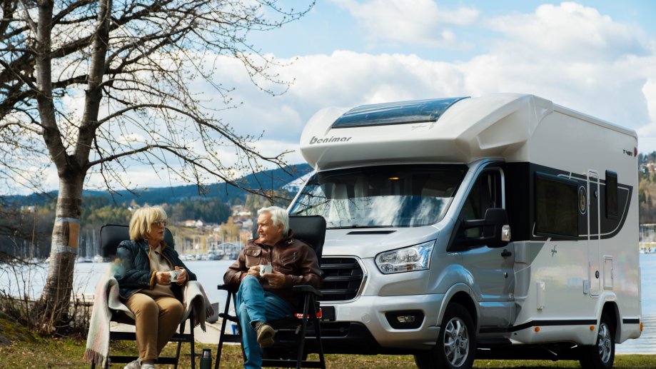 Et eldre ektepar sitter utenfor bobilen sin og nyter en kopp med kaffe.