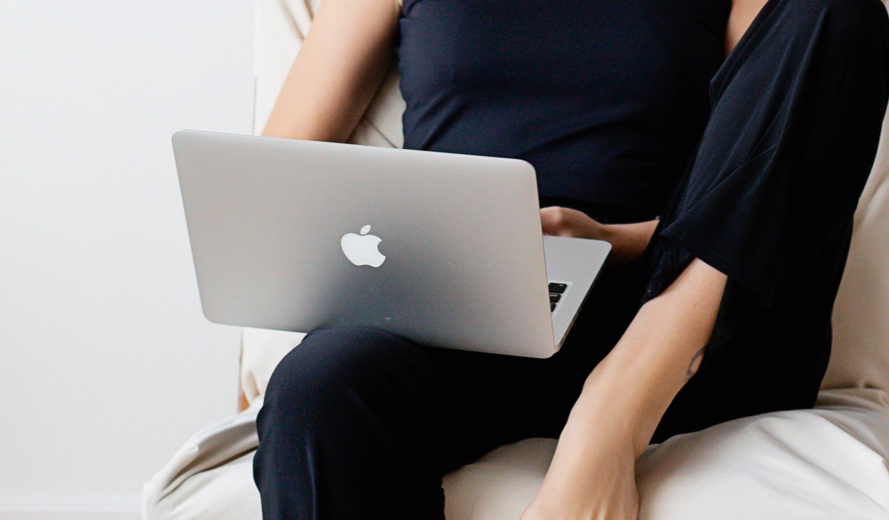 En dame sitter med en Mac lap top i fanget