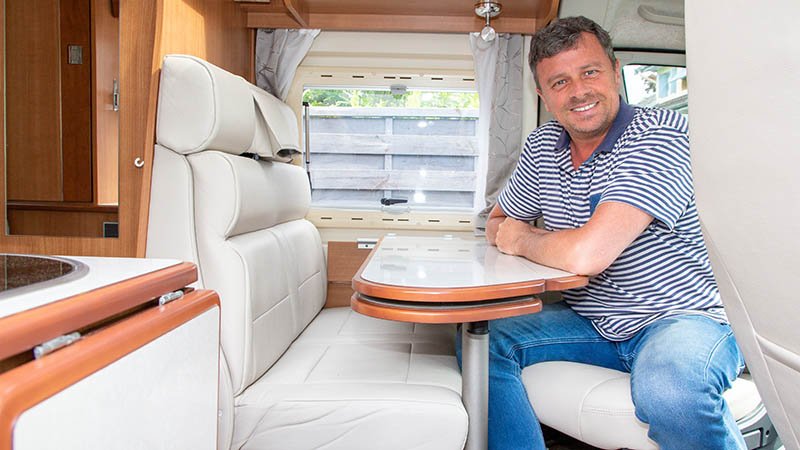 Mann sitter ved bord inne i en bobil.