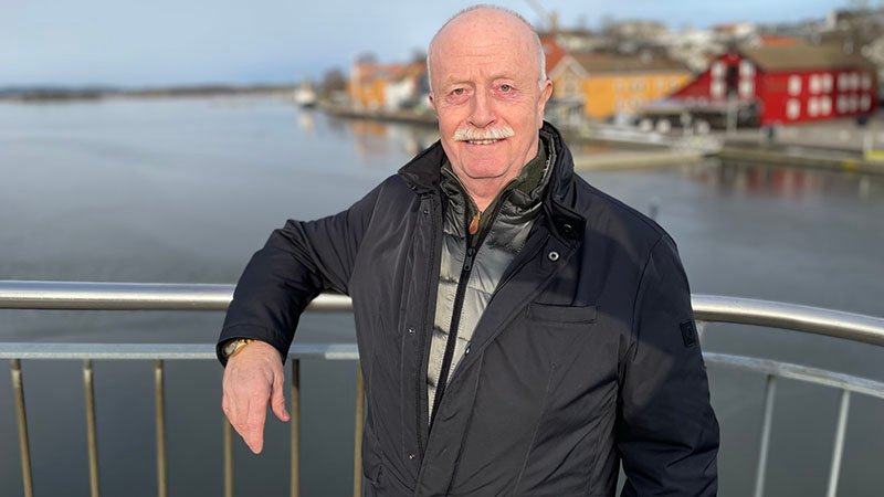 Tormod Gran står ved en brygge, ut mot vannet, med bygninger i bakgrunnen.