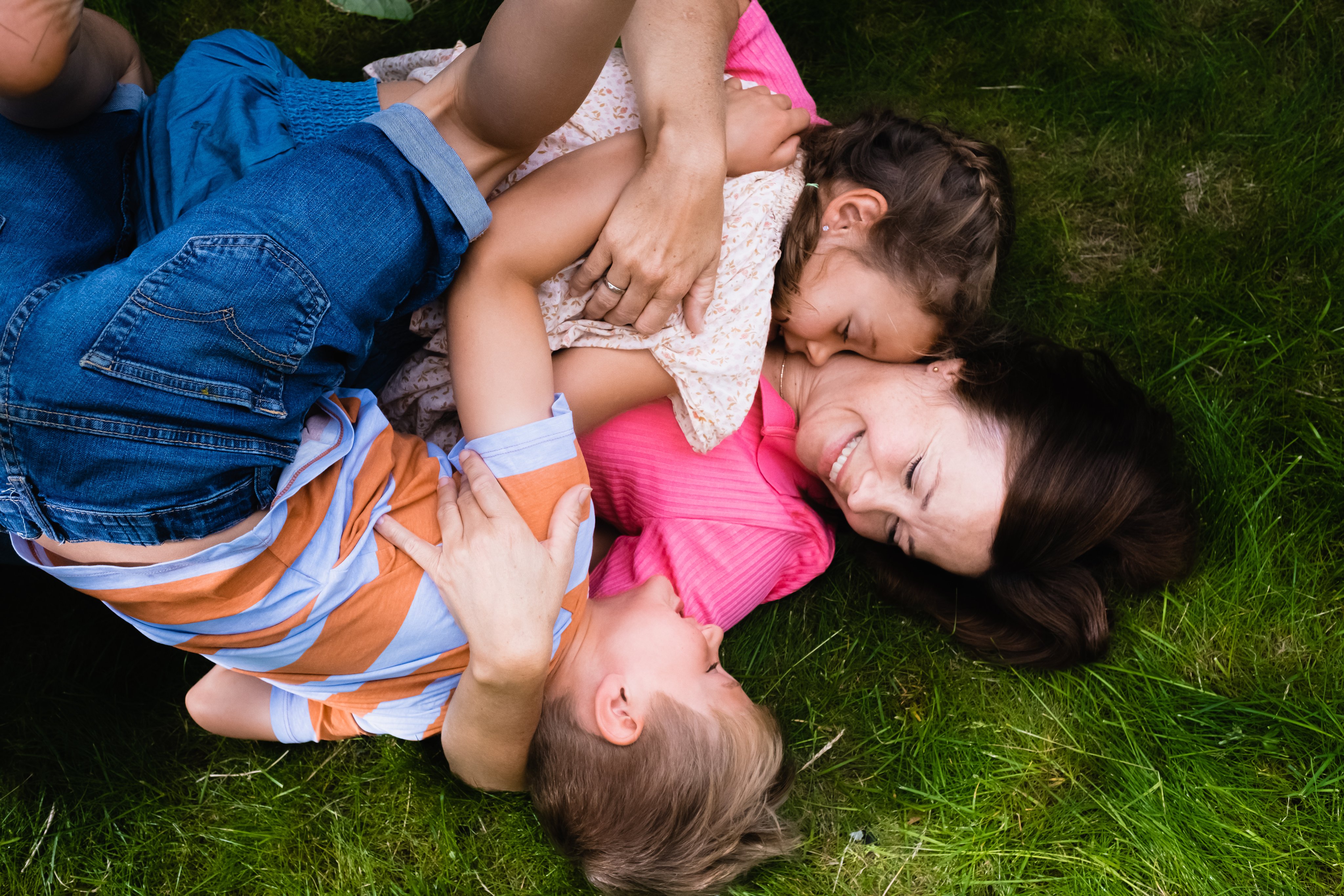 Illustrasjonsfoto smart sparing til barn. Familie som ligger og leker på gresset.