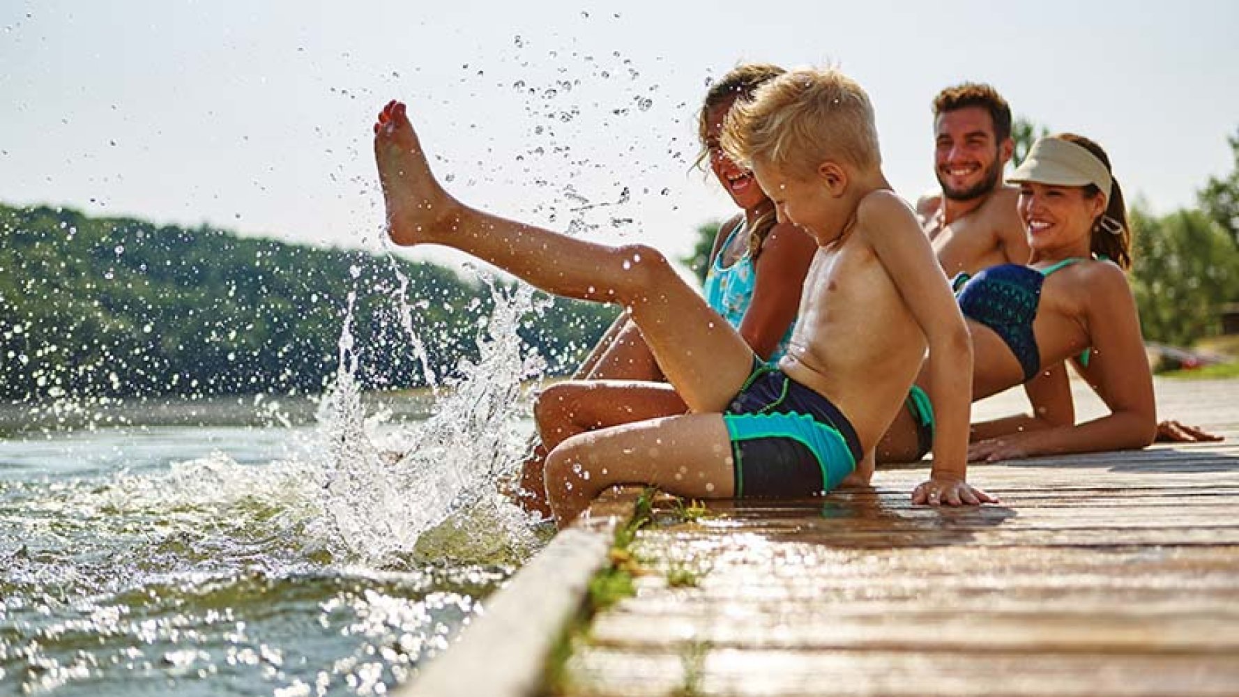 Barn leker ved vannet på en brygge en fin sommerdag.