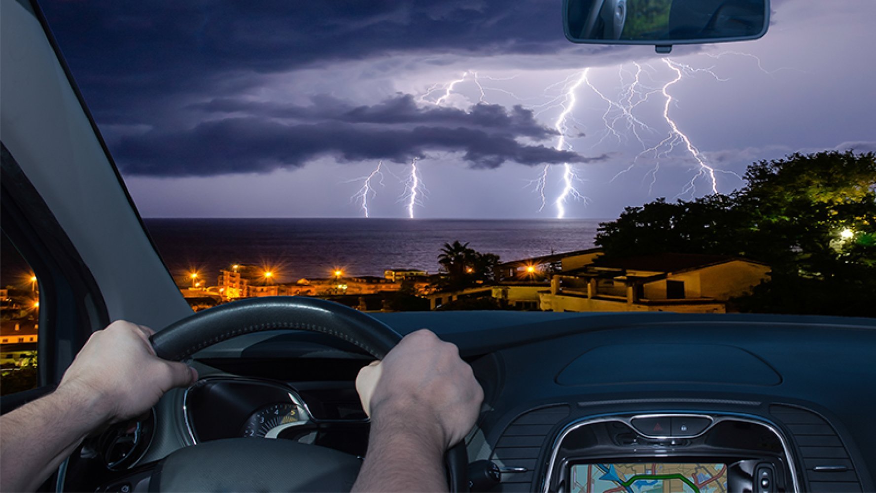 Bilde innefra en bil og ut på tordenvær og lyn.