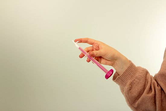 En hånd holder en hjemmetest for livmorhalskreft.