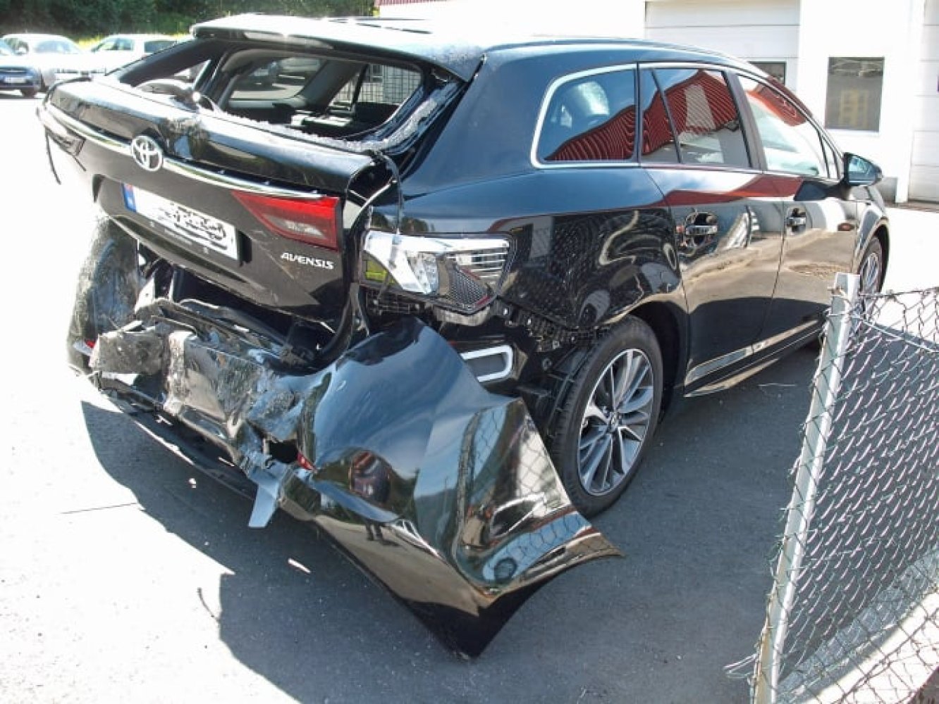 En bil med kraftig skade på bakre del etter kollisjon, bakfangeren er revet av og bakruten knust.