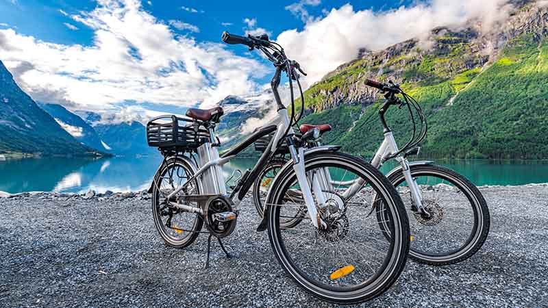To elsykler står parkert ved en fjord.