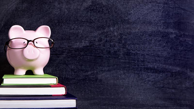 En rosa sparegris med briller står på en bokstabel