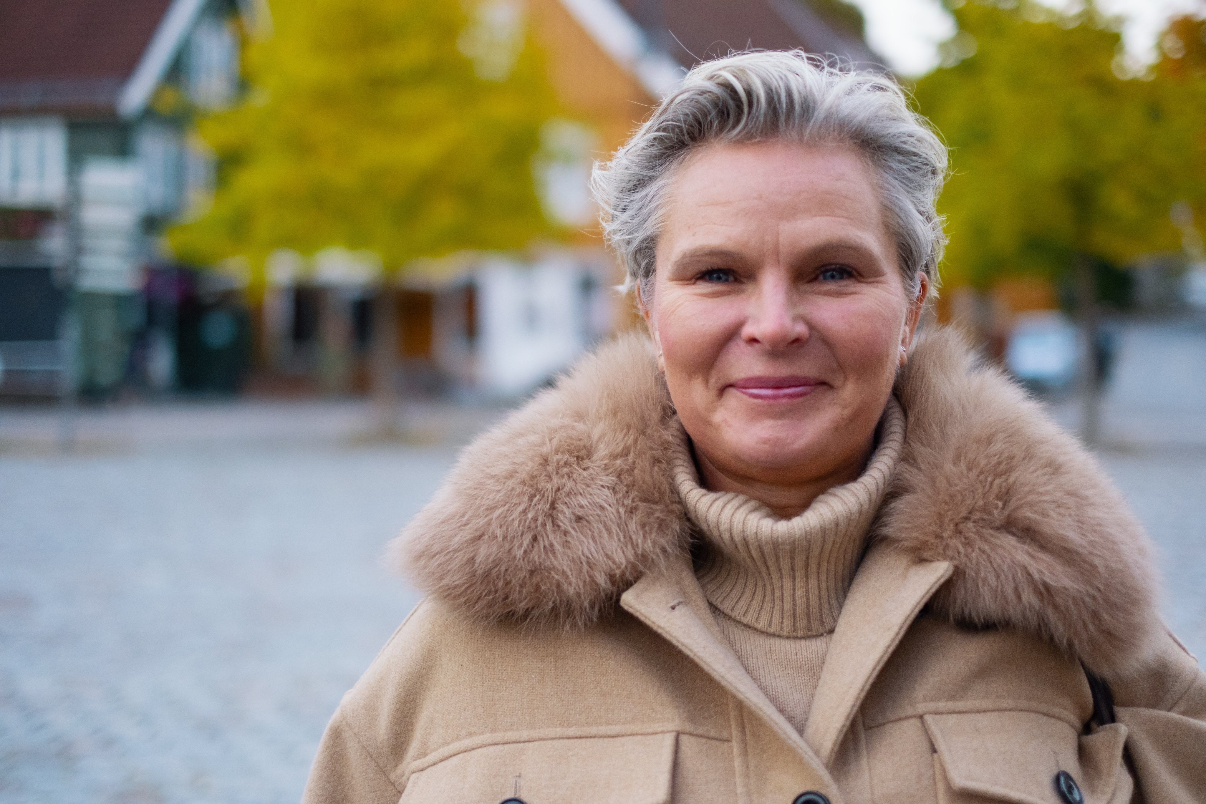 En kvinnelig ansatt smiler til kamera utendørs.