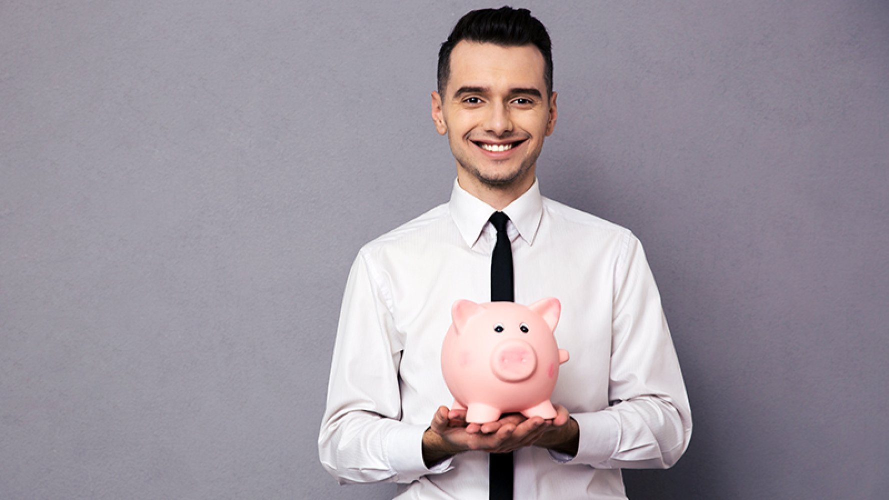 En ung mann i skjorte og slips holder en sparegris foran seg.