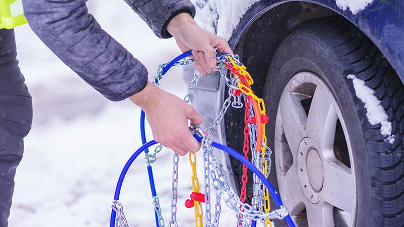 En person fester kjetting på bildekk.