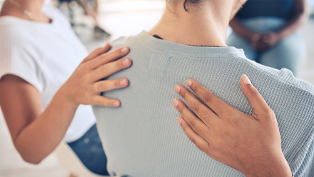 To personer legger hendene sine på en dames skuldre.