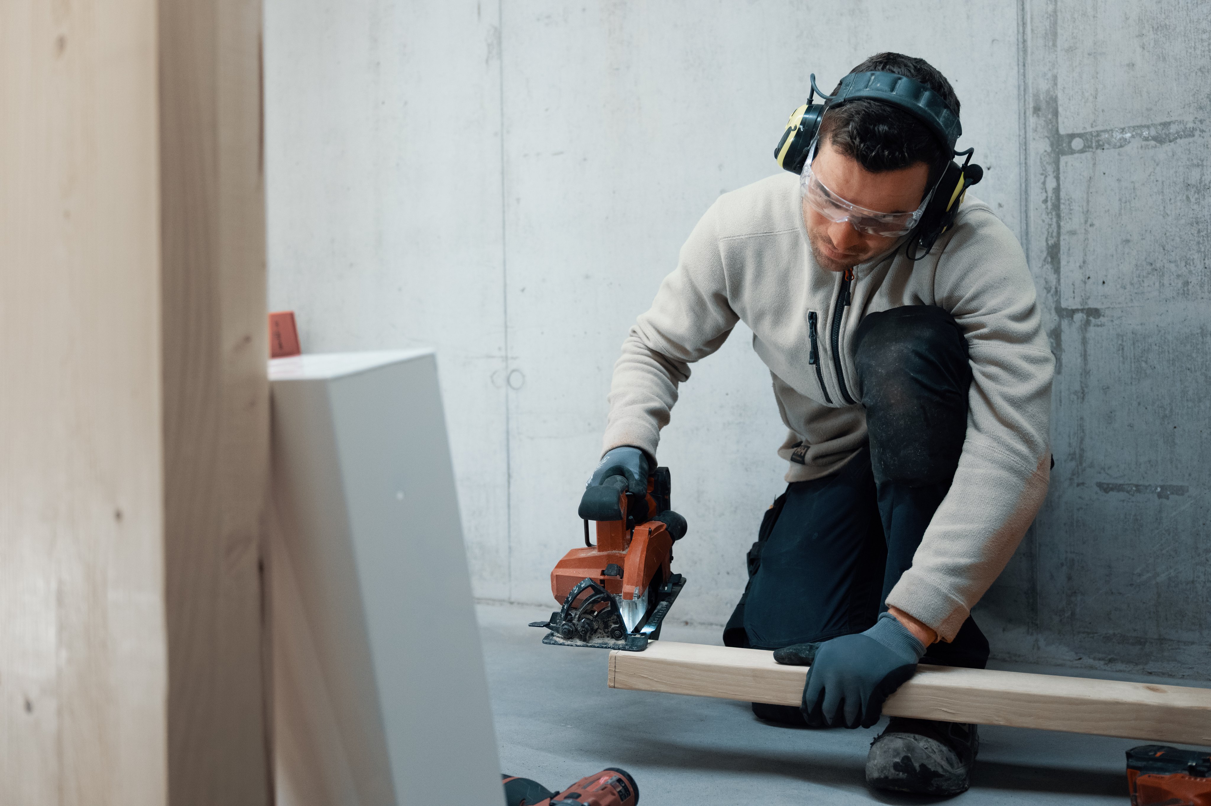 Snekker som bruker sag og har på verneutstyr.
