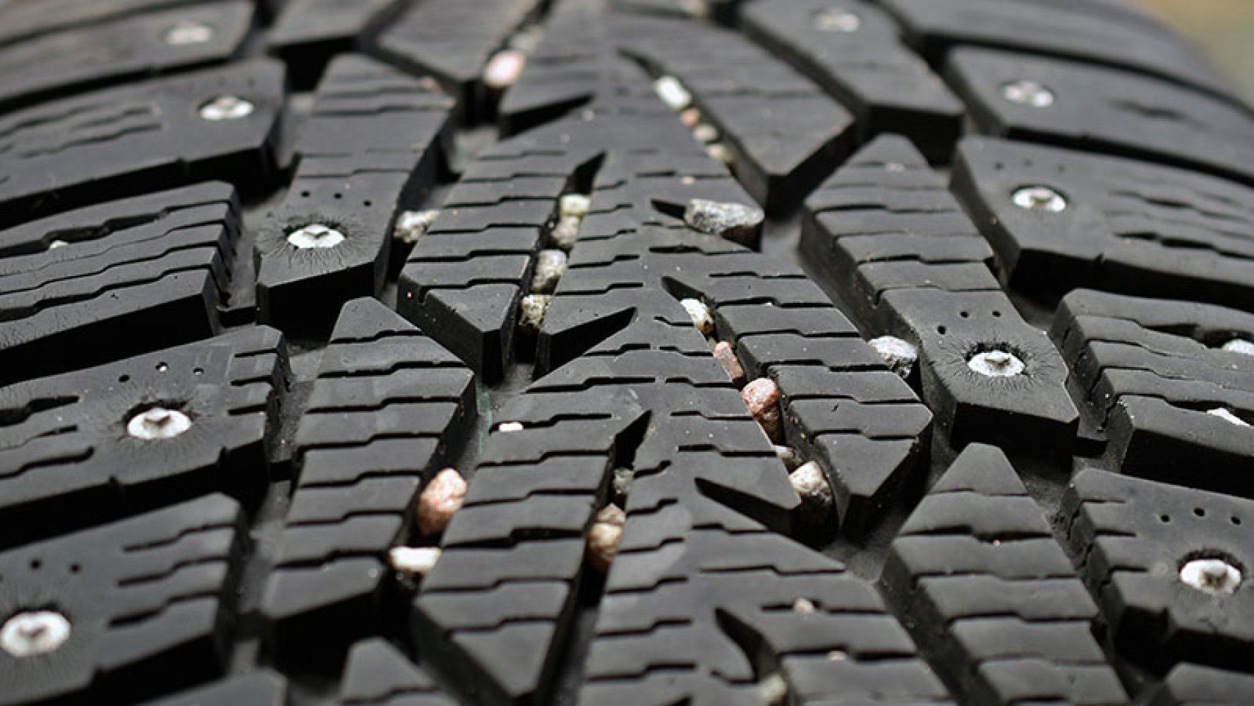 Nærbilde av et piggdekk med små steiner fast i mønsteret.