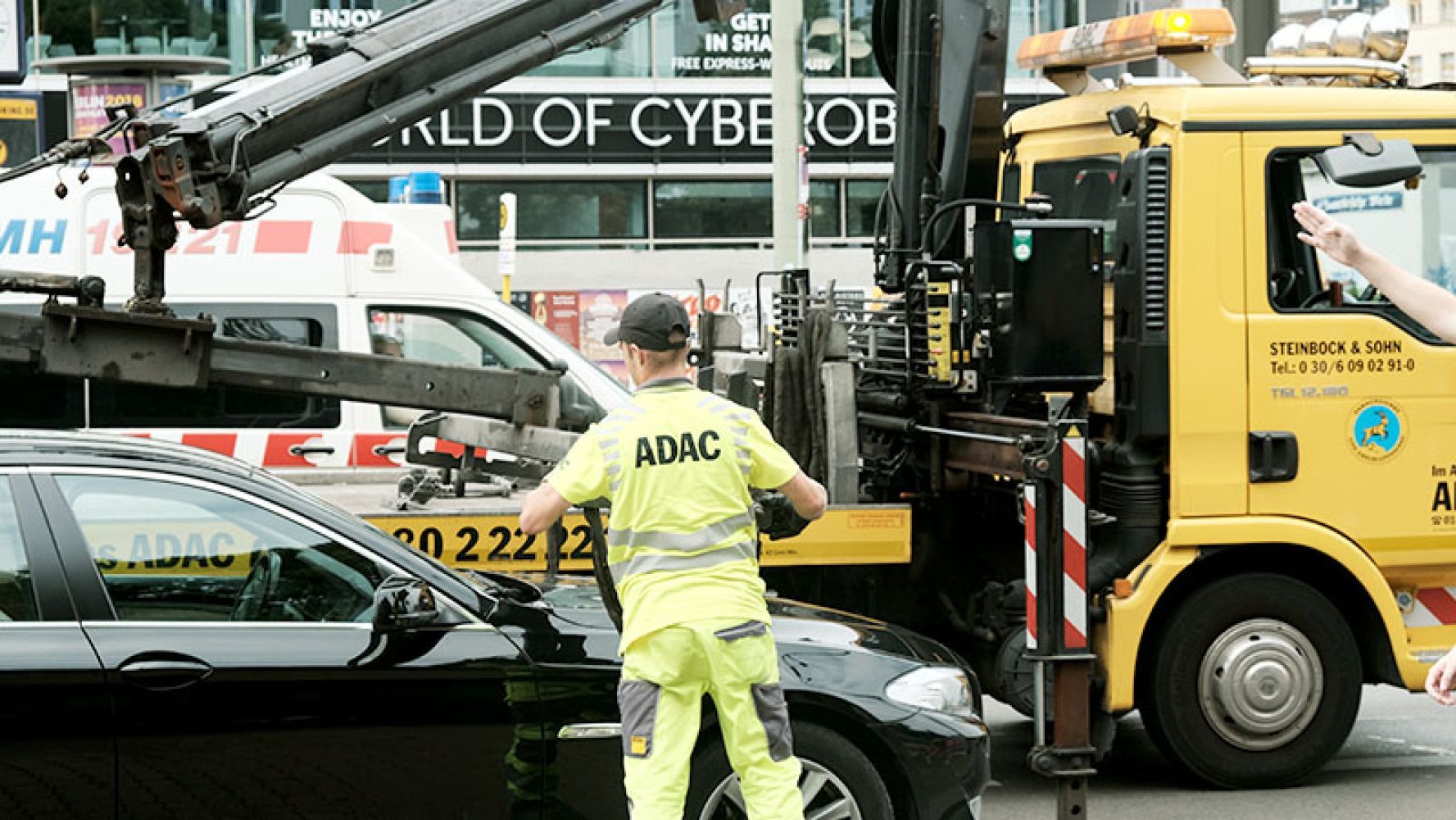 Veihjelpsarbeider sikrer en bil til en bergingsbil med kran.