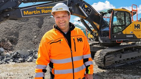 Svein-Erik på et anleggsområde foran en gravemaskin.