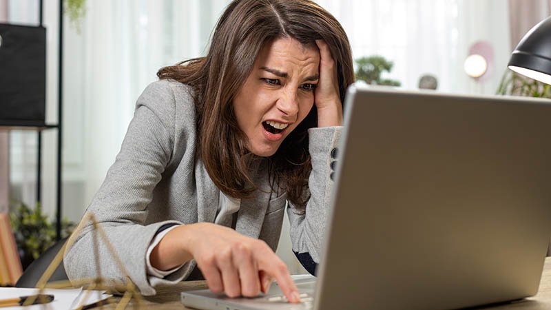 Person i dress sitter ved skrivebord og peker på tastaturet