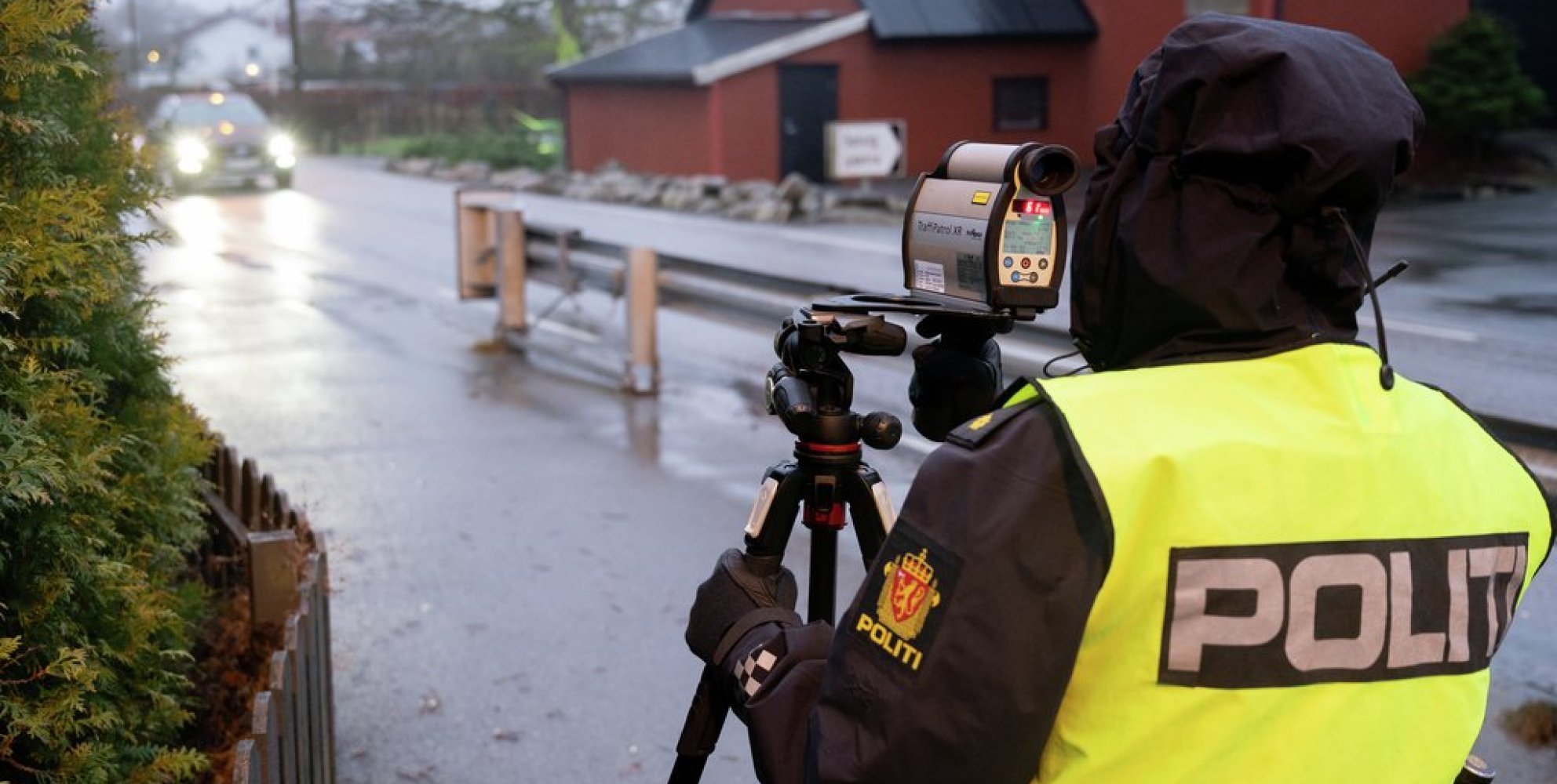 Politiet står med fartsmåler langs en liten vei.