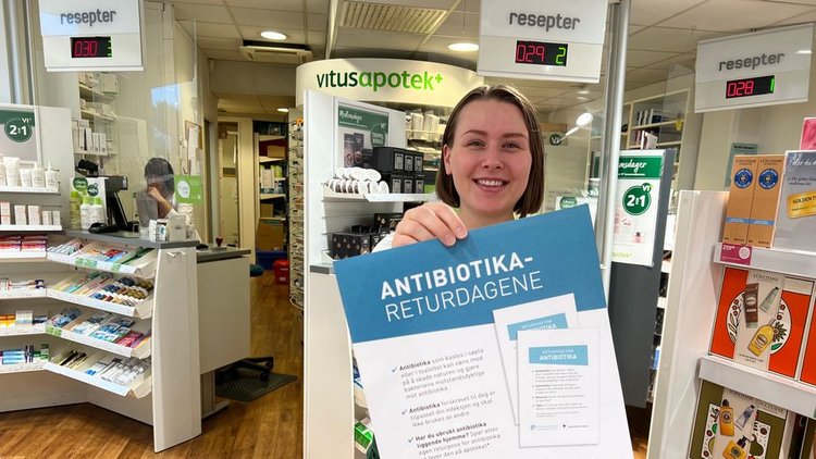 Liv Vidas i Vitusapotek holder opp en plakat om antibiotika-returdagene.
