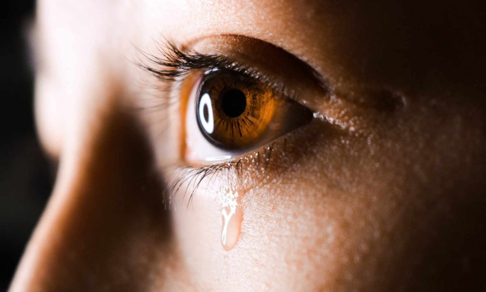 Nærbilde av et brunt barneøye som det renner en tåre fra