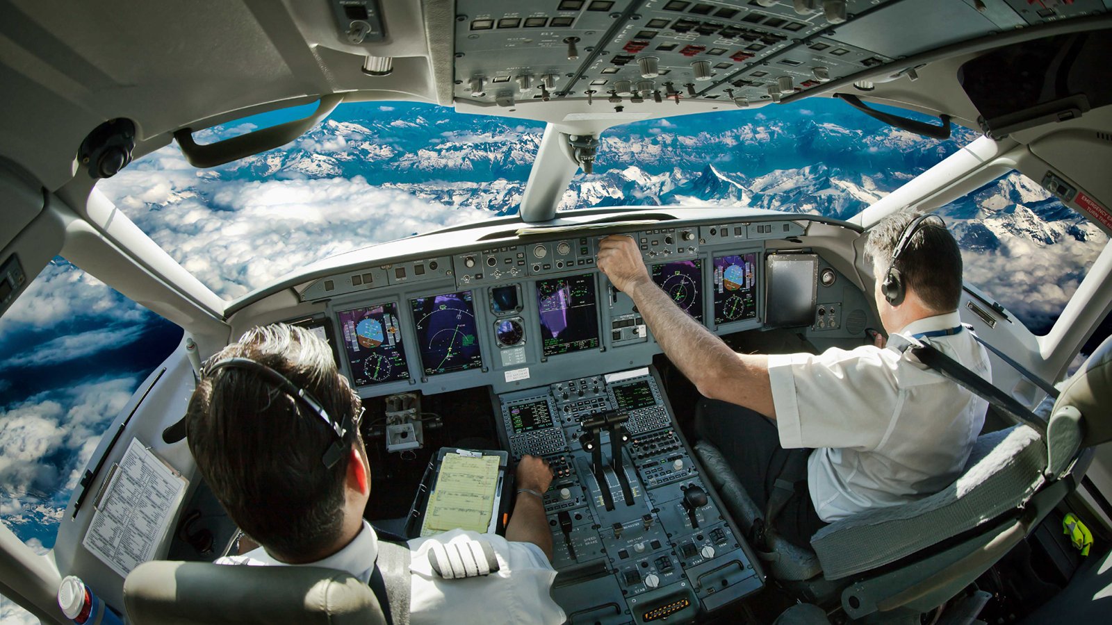 Blick in ein Flugzeugcockpit mit Piloten, die das Cockpit bedienen.