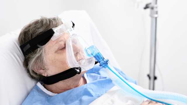 戴着口鼻面罩卧床的病人
