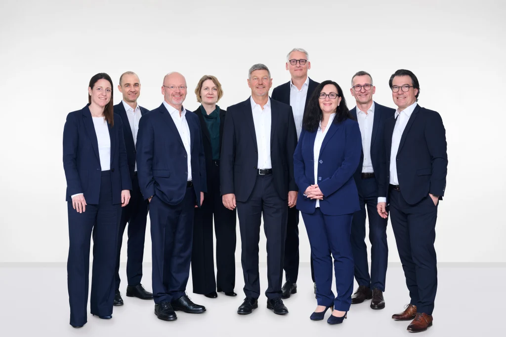 Gruppenfoto des erweiterten HUBER+SUHNER Executive Managements. Drei Frauen und sechs Männer in Anzügen stehen nebeneinander.