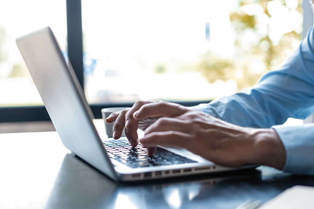 Image of man's hands typing at a laptop. Selective focus