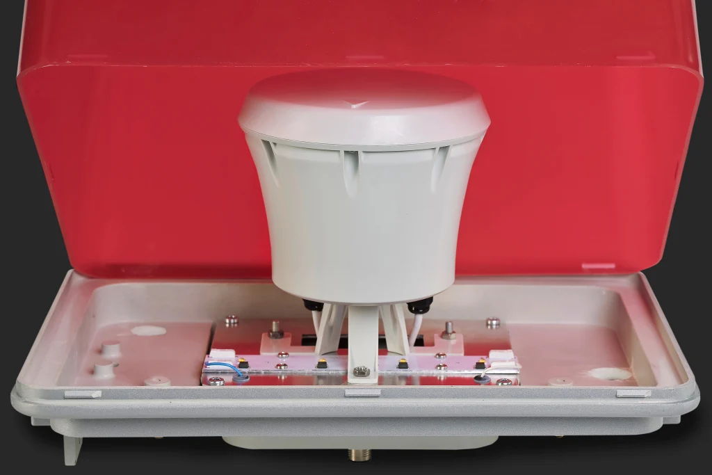 White antenna installed in an open red protective enclosure, with visible mounting hardware and internal components.