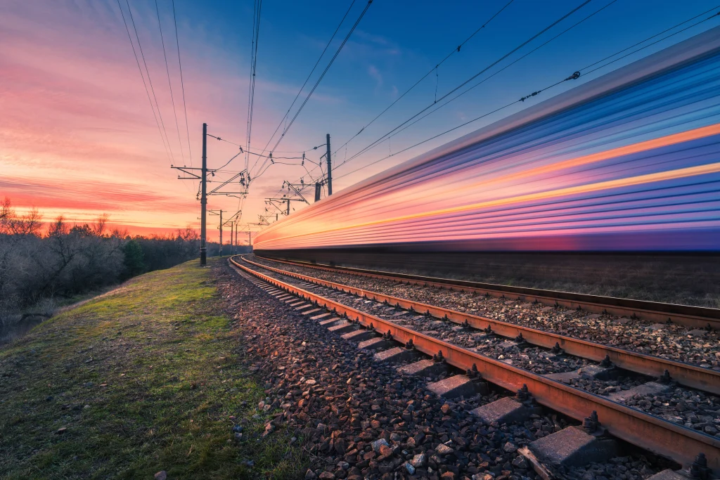High speed passenger train in motion on railroad at sunset. Blurred modern commuter train.