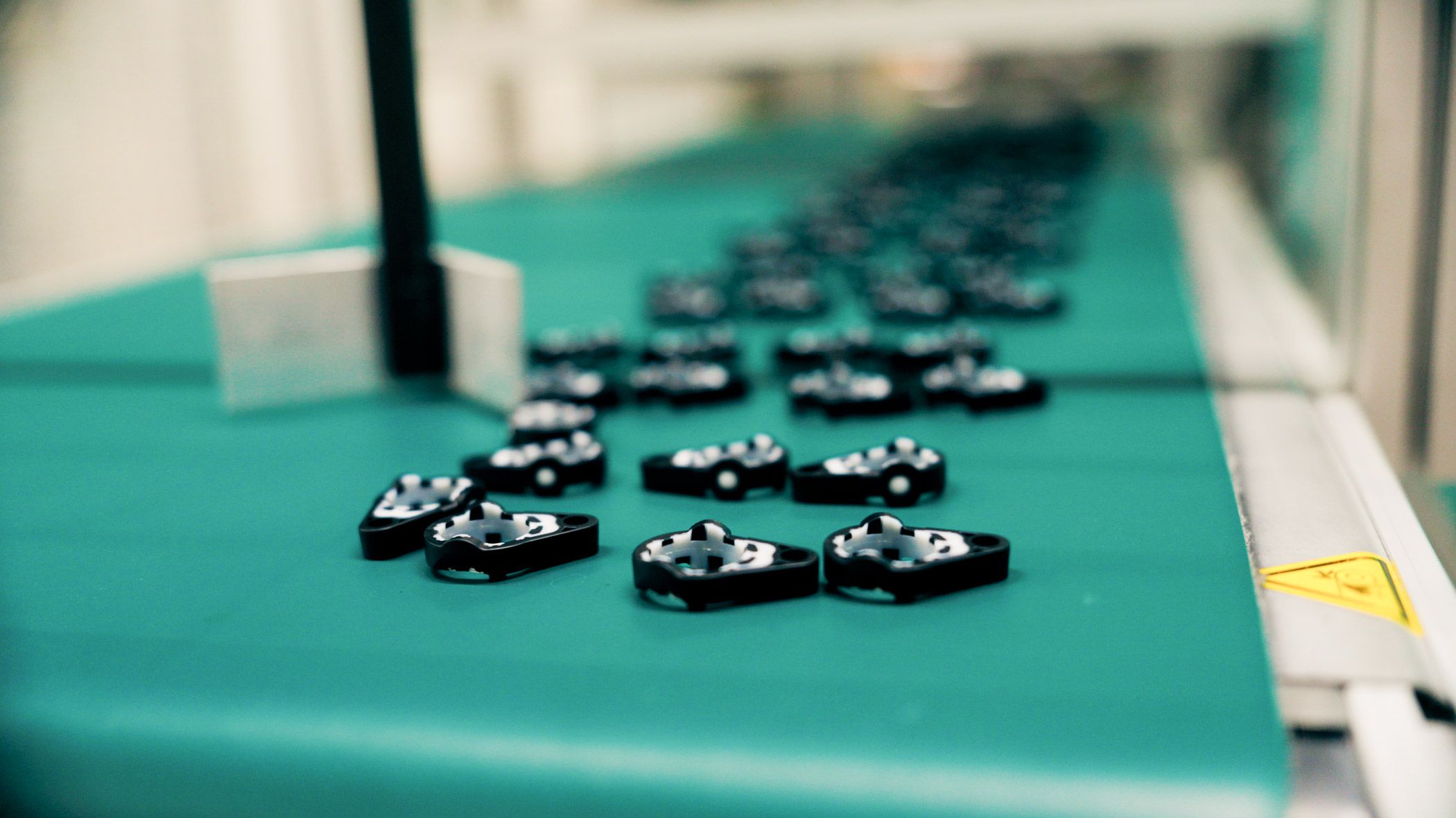 Small black connectivity components arranged on an automated production conveyor belt.