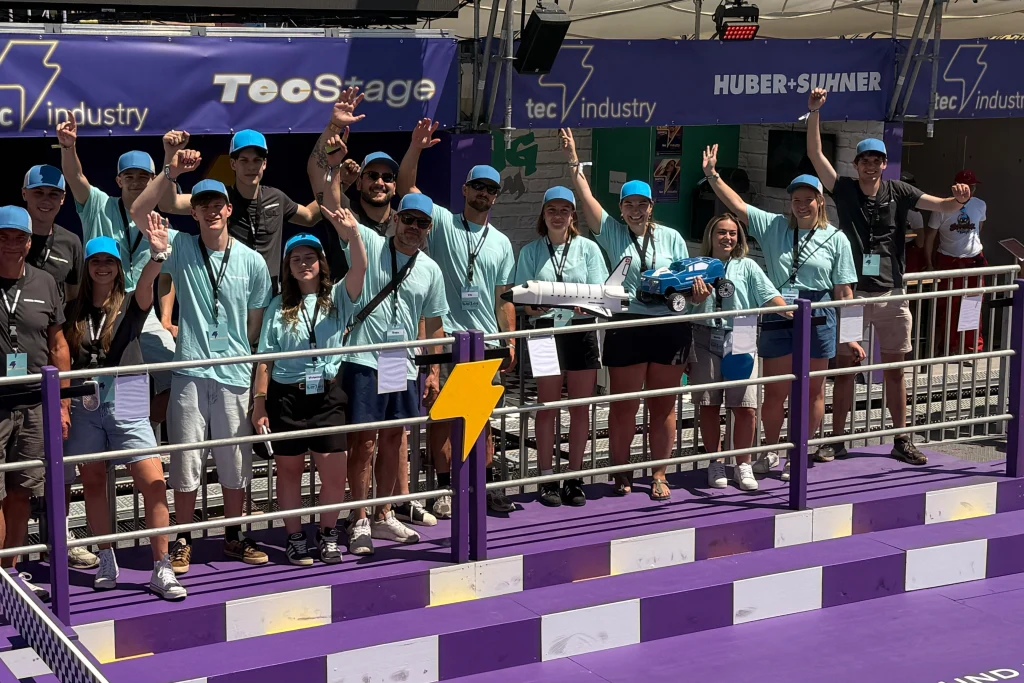Eine Gruppe von Menschen in einer Festivalumgebung posiert für ein gemeinsames Gruppenfoto.