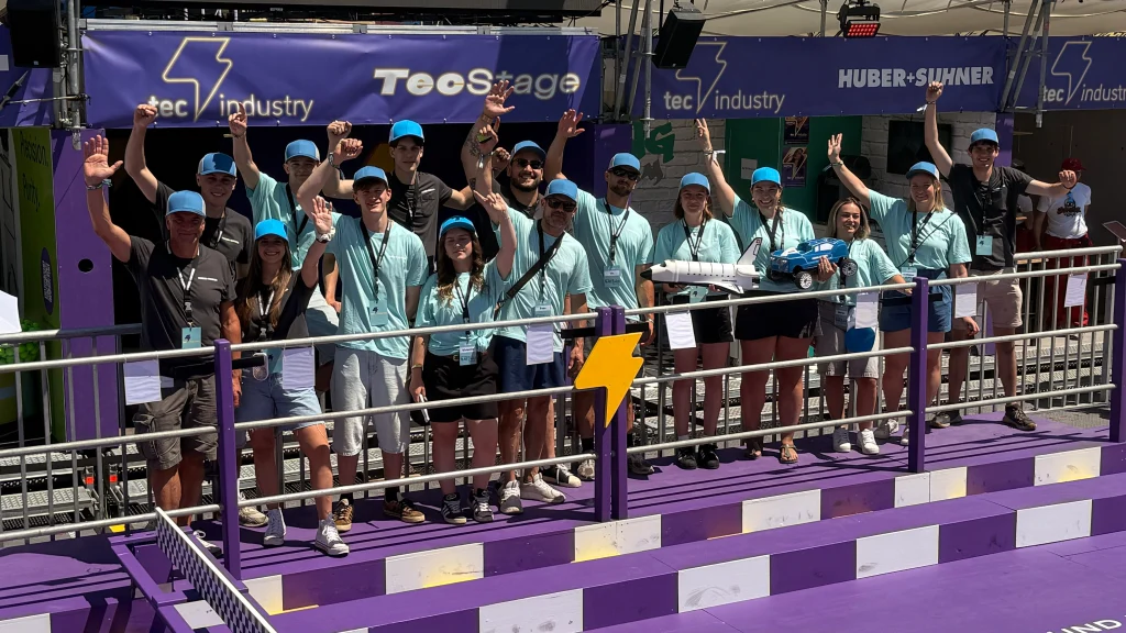 Eine Gruppe von Menschen in einer Festivalumgebung posiert für ein gemeinsames Gruppenfoto.