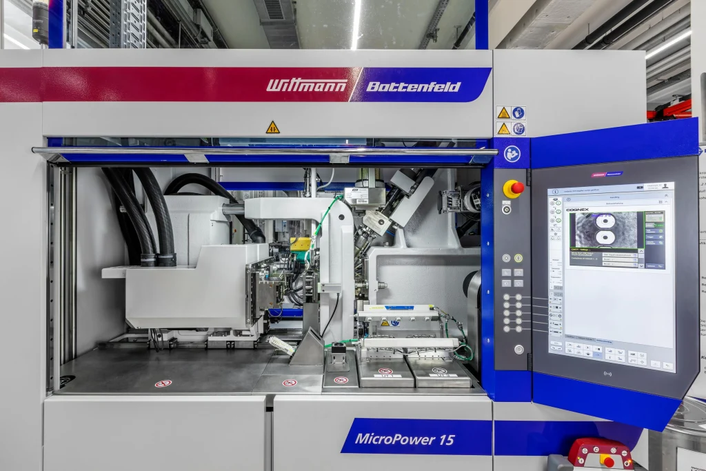 Wittmann Battenfeld MicroPower 15 micro injection moulding machine with integrated automation and digital control panel in a clean manufacturing environment.