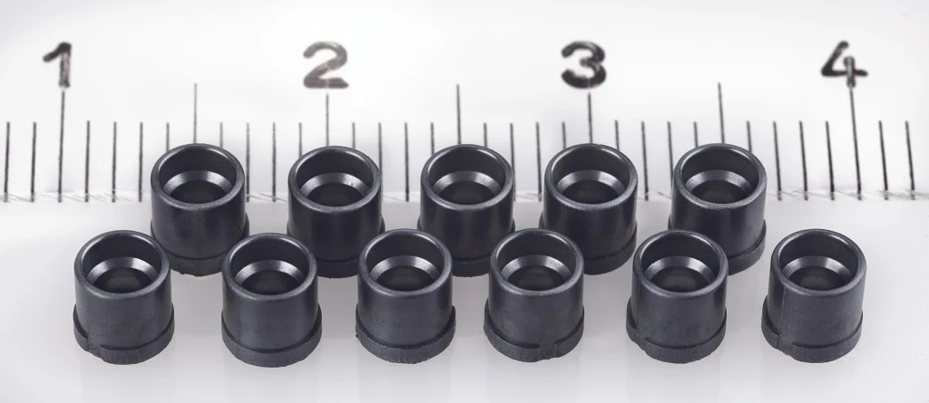 Injection-moulded plastic bushings with measurement scale demonstrating high-precision production of miniature components.