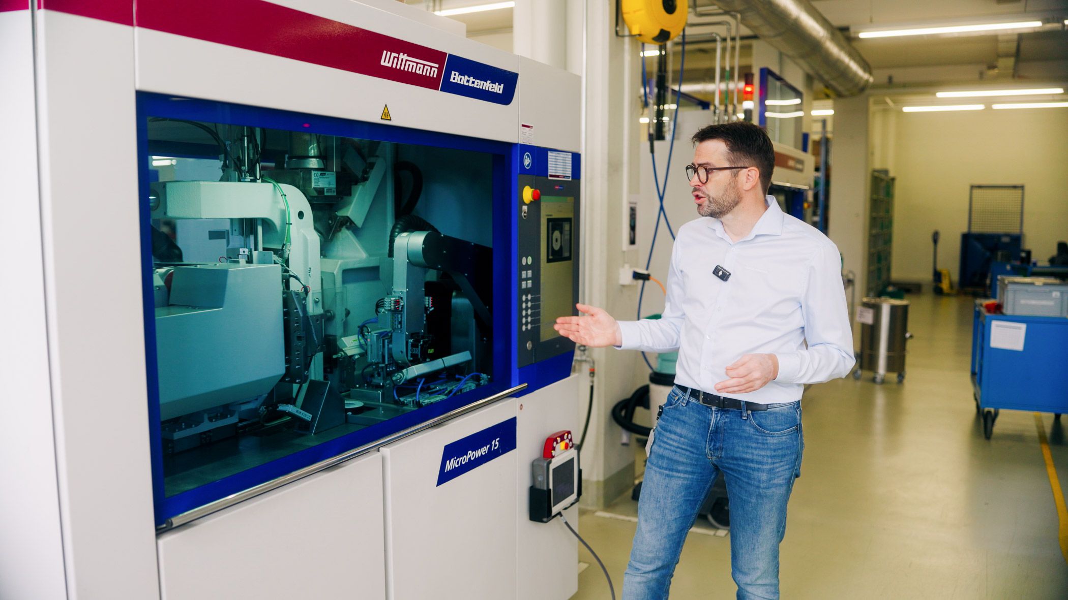 Industrial manufacturing machine operating in a production facility with an employee explaining the process.