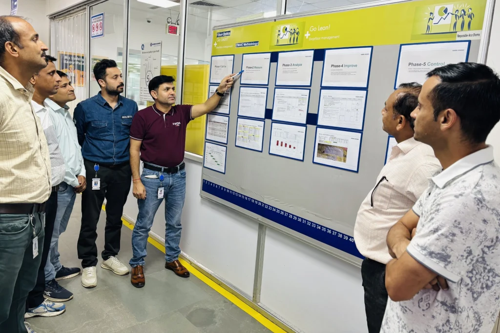 Generating response&nbsp; Copilot said:  Teammitglieder überprüfen Kennzahlen zur Prozessverbesserung und Projektdokumentationen an einem Whiteboard in einer Produktionsstätte.