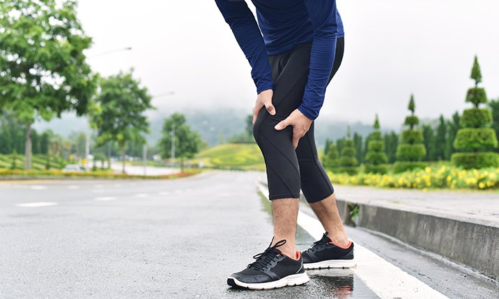 A runner holding on to his knee mid-run in pain knee-osteoarthritis-when-to-see-specialist
