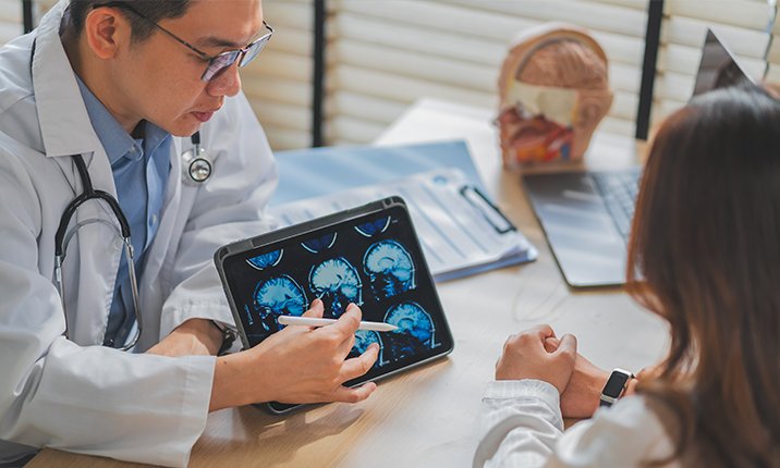 Specialist showing patient brain scans, and discussing treatment. brain-aneurysm-deciding-treatment