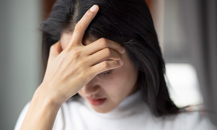 A woman holding her head in pain due to a thunderclap headache brain-aneurysm-emergency-symptoms