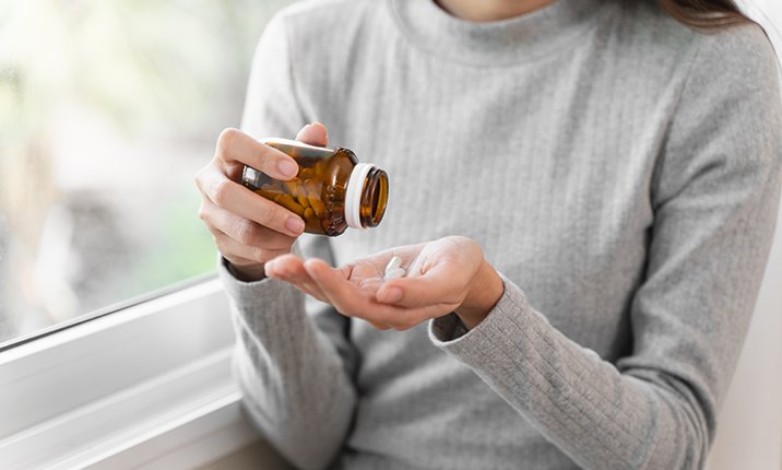 Lady pouring medication tablets onto her palm brain-aneurysm-post-treatment-medications