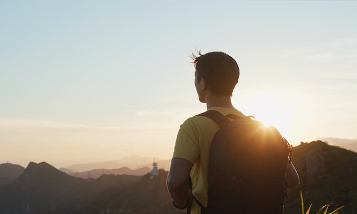Man go hiking and look at the beautiful sunset view on mountain