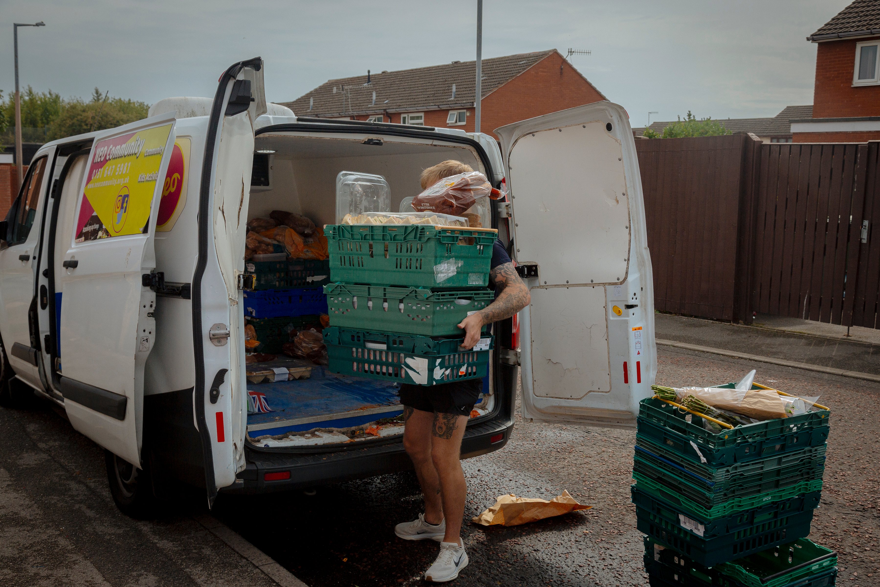 Person obscured by boxes of food donations they're carrying out of a van for food bank.