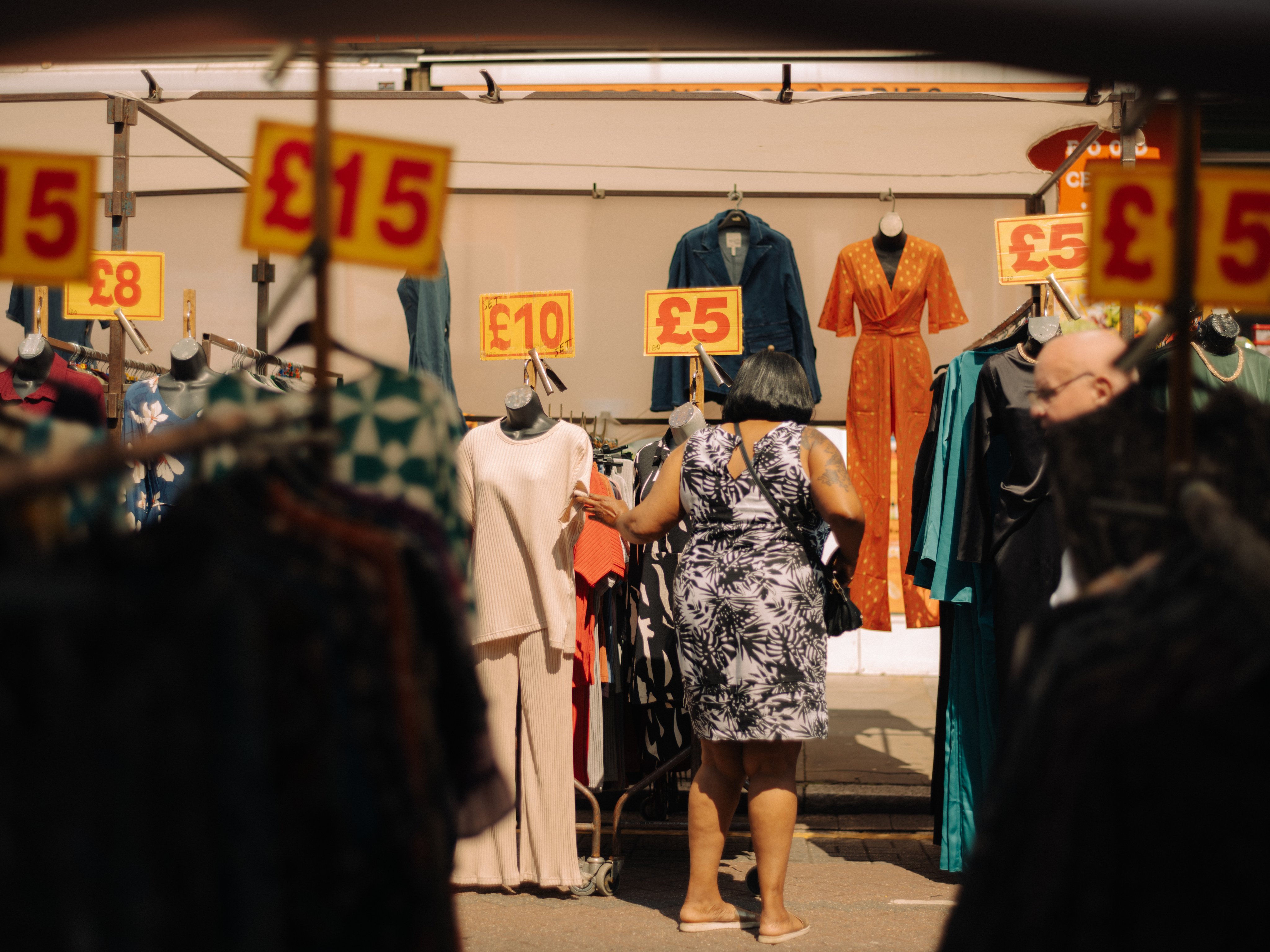 Back of woman browsing clothes in outdoor market.