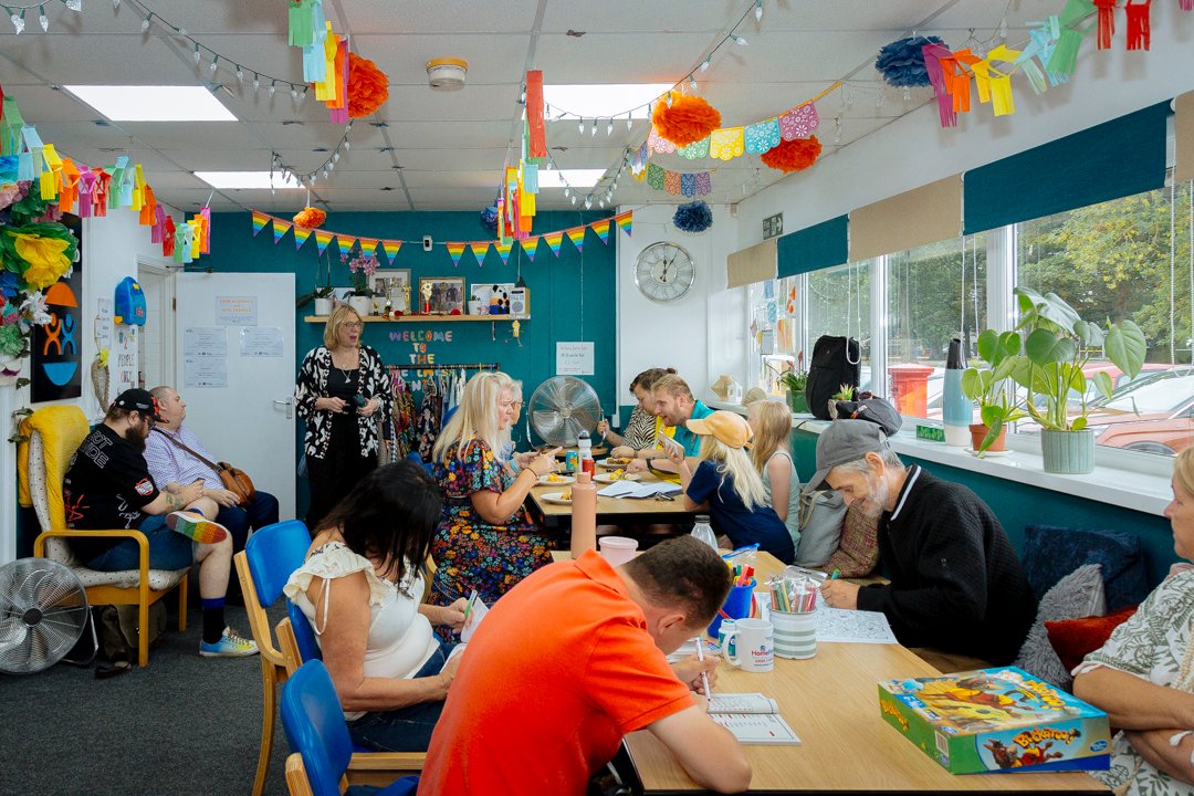 Community centre where adults and children are sat at tables doing activities